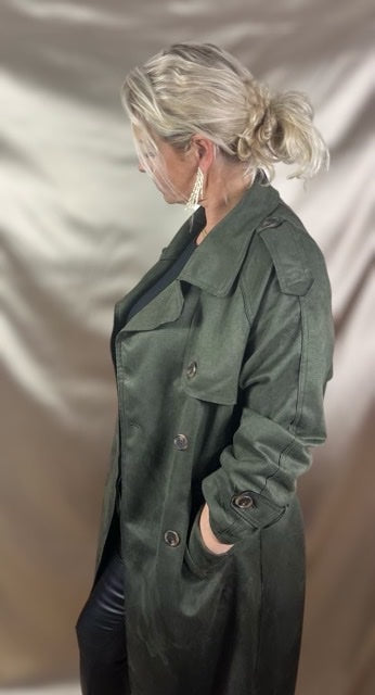 Model iført grøn trenchcoat fra siden– effortless cool i lækre lag.