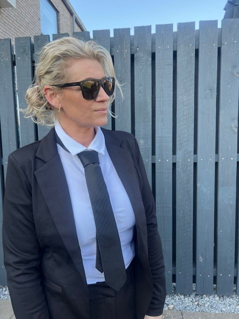 Sort slips til kvinder – klassisk og cool accessorie, stylet med hvid skjorte og sort blazer.