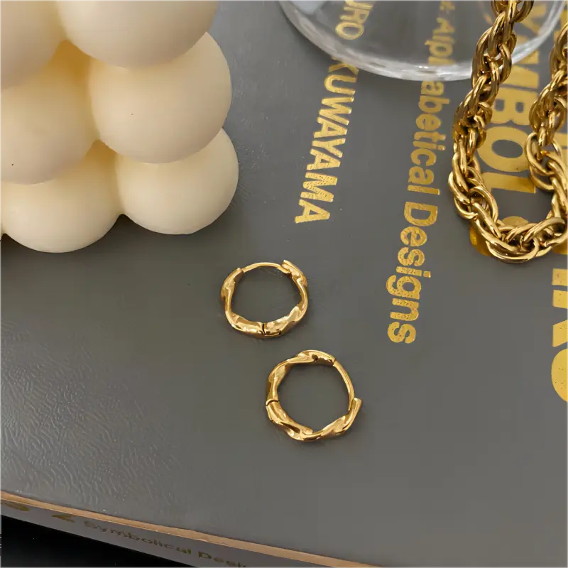 Snoede hoops i guldbelagt rustfrit stål med unik bølget struktur – elegant design fra SpohrCopenhagen.