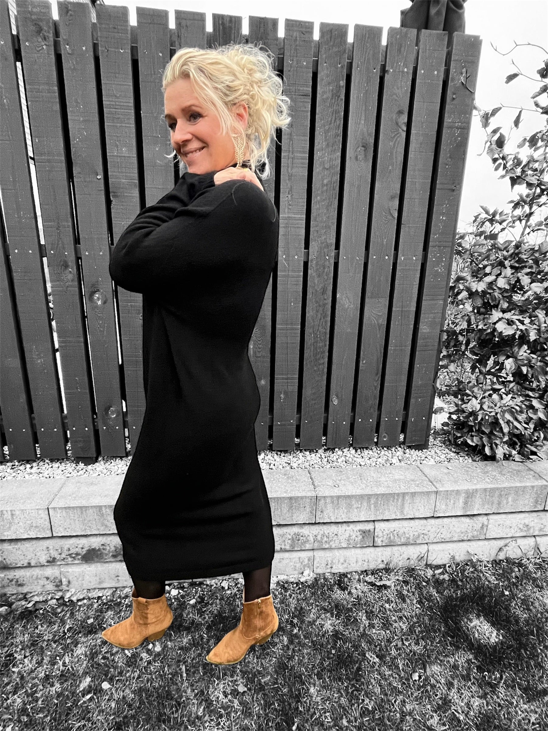 Sideprofil af modellen, der fremhæver kjolens afslappede pasform og dristige sideslids.