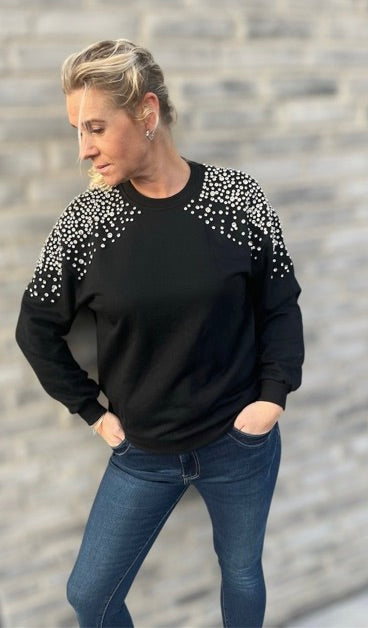 Sort sweater med similisten-detaljer fra Spohr Copenhagen, fremhæver elegant design og komfort."​