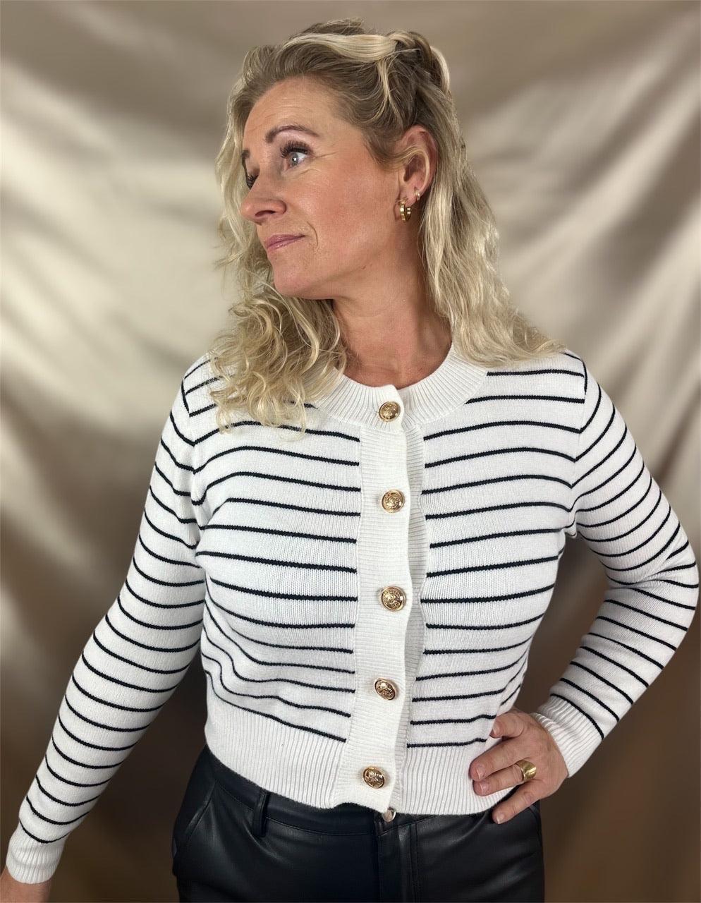 ​Model iført hvid og sort stribet cardigan med elegante guldknapper – en maritim klassiker med et strejf af glamour.