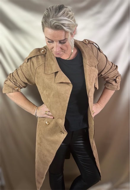 Model i camel-farvet suede trenchcoat med dobbeltradede knapper og justerbart taljebælte – klassisk elegance møder moderne kant.