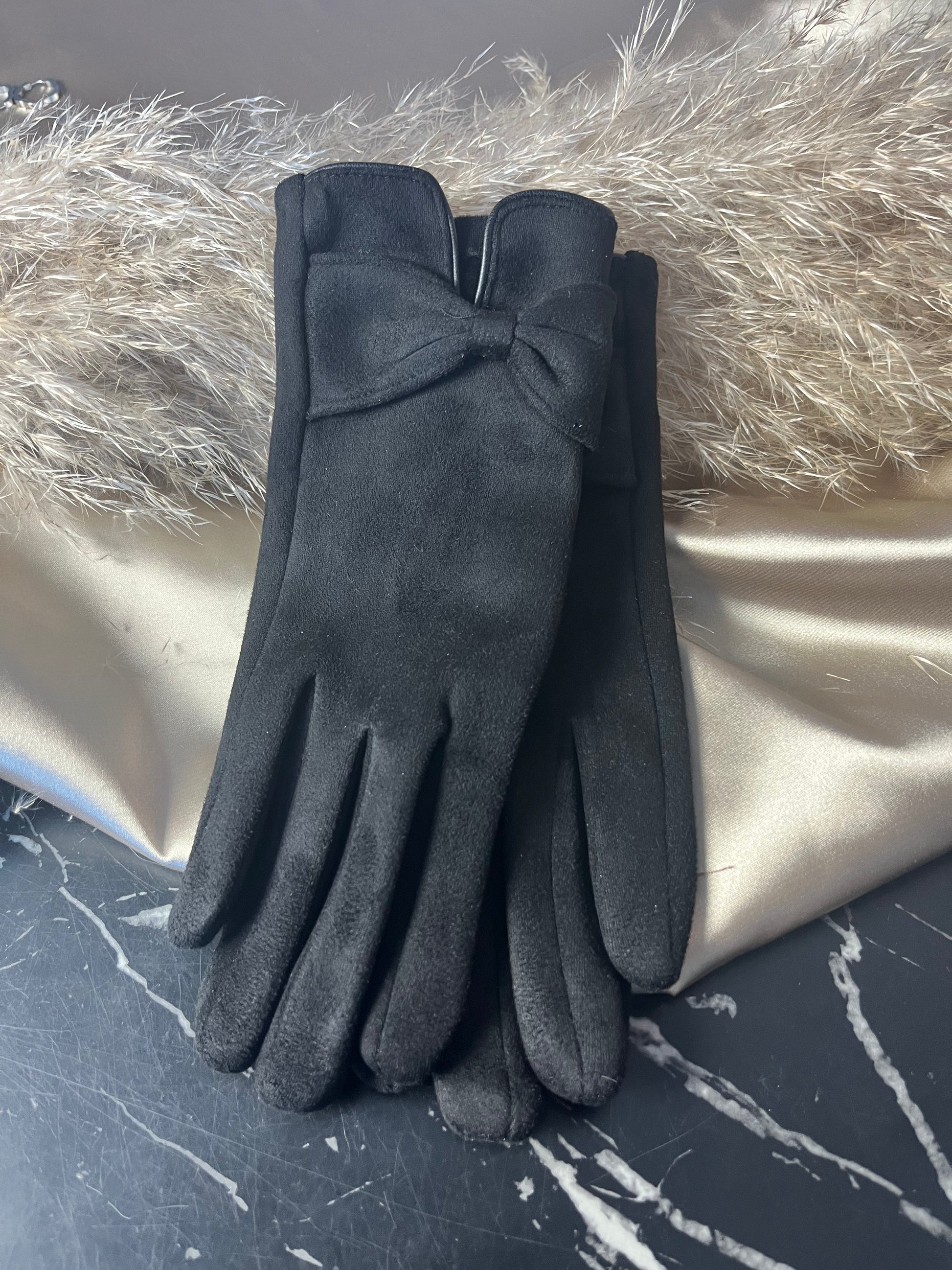 Elegante sorte handsker fra Spohr Copenhagen i blød suede med charmerende sløjfedetalje ved håndleddet – fordi dine hænder fortjener lidt luksus