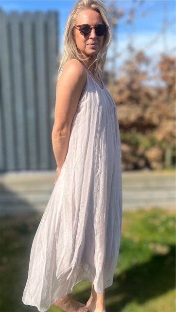 Kvinde iført lang, lys sommerkjole i silke-viskose – luftigt og feminint look i sollys