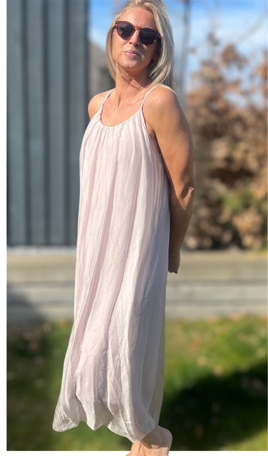 Kvinde iført lang, lys sommerkjole i silke-viskose – luftigt og feminint look i sollys