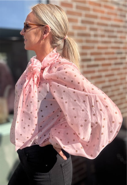 Sideprofil af rosa ballonærmebluse med prikker og sløjfe – luftigt og sofistikeret